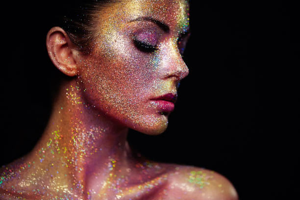 Portrait of Beautiful Woman with Sparkles on her Face. Girl with Art Make-Up in Color Light. Fashion Model with Colorful Makeup