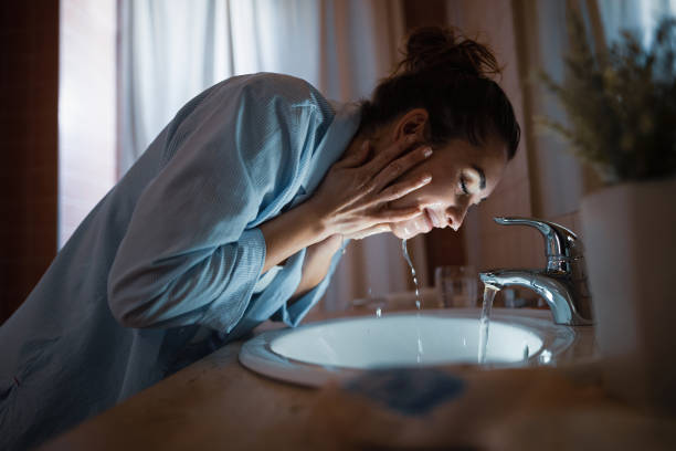 Young smiling woman washing face in the bathroom.